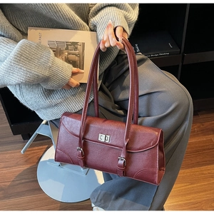 Close-up of vintage burgundy textured leather bag with silver buckle and turn-lock