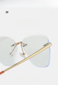 Macro detail of rimless anti-blue light glasses with gold metal hinges and tortoise temple tips
