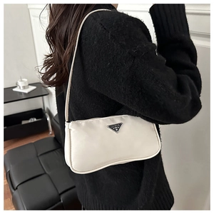 Close-up of white nylon hobo bag featuring a metal triangle logo on a black sweater