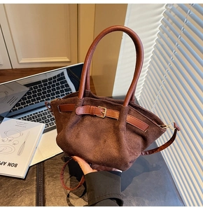 Detail of dark brown suede bucket bag with long handles and golden buckle adjustment
