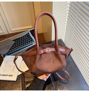 Detailed close-up of dark brown suede handbag with leather buckle and elegant strap