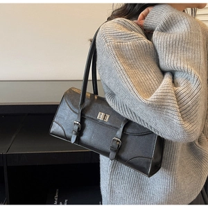 Detail of black glossy leather underarm bag with silver turn-lock and buckle strap design