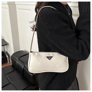 Detail of a cream nylon baguette bag featuring a metal logo plate and slim shoulder strap
