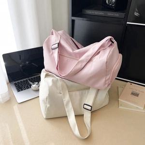 Large capacity nylon sports gym and travel duffel bags in pink and cream on a desk