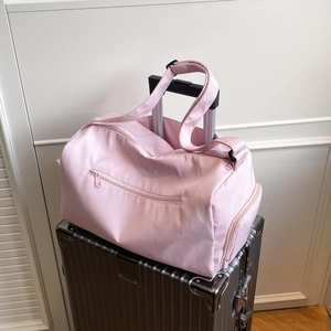 Pink waterproof fitness travel bag with luggage sleeve attached to a silver suitcase