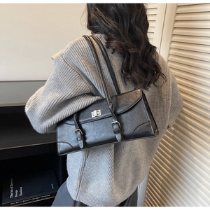Detail of black leather pillow bag featuring silver twist lock and adjustable straps