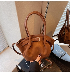 Close-up of brown faux suede handbag showing smooth leather straps and decorative buckle