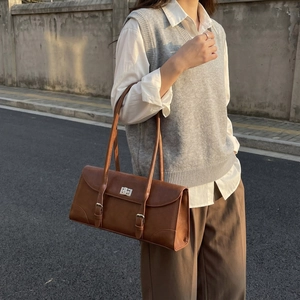 Retro brown underarm shoulder bag with metal buckles shown in an outdoor street style shot