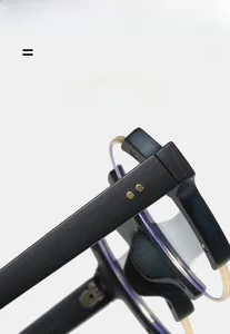 Macro detail of wood-textured eyeglass frame hinge with golden rivets and blue light lens