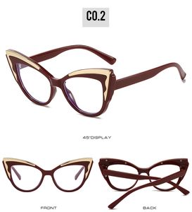 Macro detail of cat-eye eyewear showing dark red frame and golden metal accents