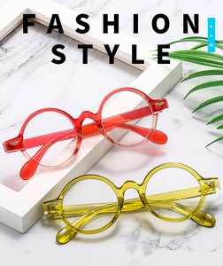 Detail of oval gradient resin glasses frames with gold metal hinges on marble background