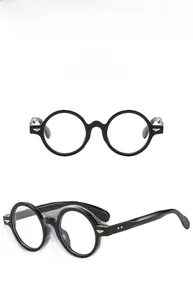 Detail view of oval retro black glasses frames with gold wing metal hinges on the temples