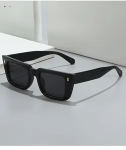 Detail of square black sunglasses with golden metal accents on a minimalist background