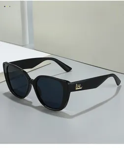 Détail de lunettes de soleil œil-de-chat noires avec monture polie et logo doré sur la branche
