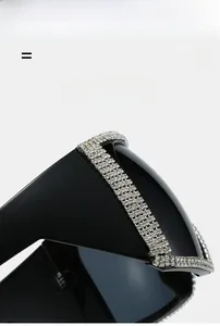 Detail of square oversized sunglasses featuring hand-set rhinestones on glossy black frame