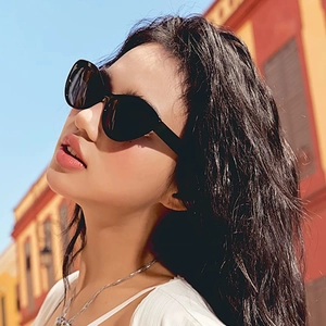 Fashionable black cat-eye sunglasses with wide frames worn by a model in outdoor light