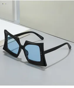 Detail of oversized black geometric sunglasses with light blue lenses and metal accents