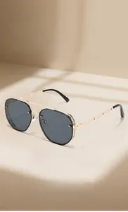 Detail of steampunk sunglasses with gold metal frame and mesh side shields on beige surface