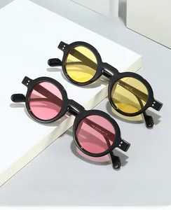 Detail of retro round sunglasses with yellow and pink lenses and metal rivet accents