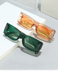Detail view of forest green and amber orange rectangular sunglasses on a white pedestal