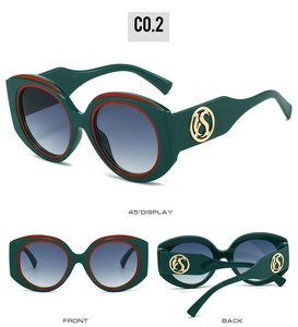Détail de lunettes ovales vert foncé avec bordure rouge et logo doré sur la branche