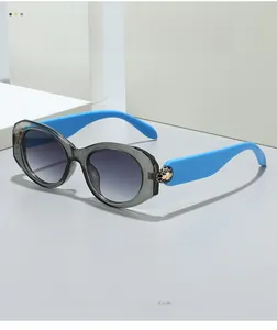 Detail of grey oval sunglasses with blue temples and golden honeycomb decorative ball