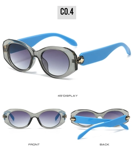Detail view of oval sunglasses with gold snake head decor and purple gradient lenses