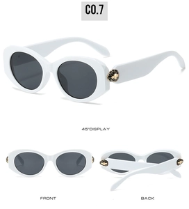 Close-up of white oval sunglasses with gold snake head hinge detail and gray lenses