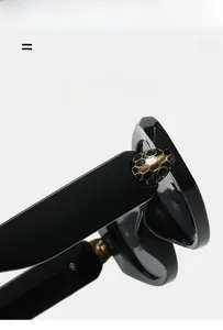 Close-up of black sunglasses with signature gold snake head decoration on the temple