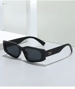 Detail of black thick rectangle sunglasses with gold metal temples on a white stand