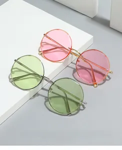 Detail of pink and green rimless round sunglasses with thin metal temples on geometric props