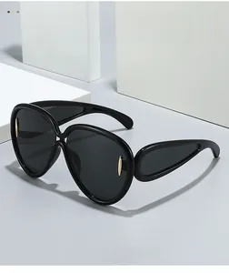 Close-up of oversized black sunglasses featuring gold metal spindle accents on the frame