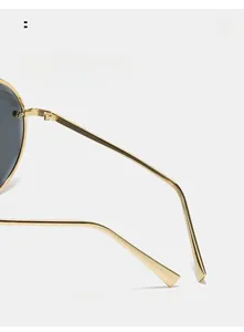 Detailed close-up of golden metal curved temple arms on stylish round sunglasses