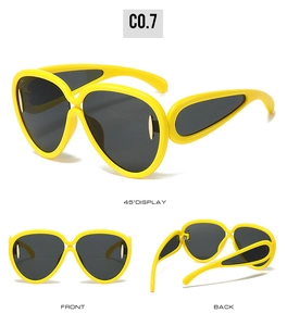 Detail view showing yellow oversized sunglasses with wave temples and gray lenses