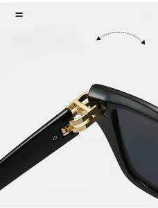 Detail eines langlebigen goldenen Scharniers mit Doppelbuchstaben-Design an der Sonnenbrille