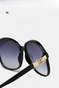 Detail of square sunglasses showing flexible hinges and gold metal H-shaped decor
