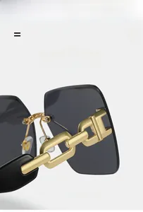 Detail of rimless sunglasses featuring a bold gold chain link temple design and gray lens