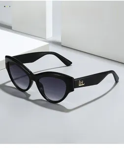 Detail of black cat-eye sunglasses with gold metal logo on temple and gradient lenses