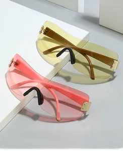 Detail of oversized shield sunglasses with gold metal hinges and amber tinted lenses