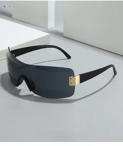 Detail of oversized shield sunglasses with gold metal hinges and gray tinted lenses