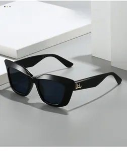 Detail of black cat-eye sunglasses featuring a gold metallic logo on the side temple