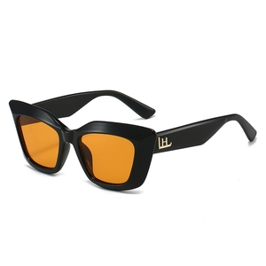 Cat eye sunglasses with black frame orange lenses and gold metal logo on temple