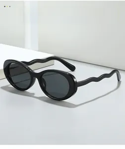 Detail view of oval retro sunglasses featuring unique black wavy temples and dark lenses