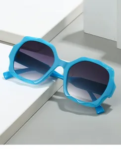 Detail of blue hexagonal sunglasses with wavy frames and gradient grey lenses on stone