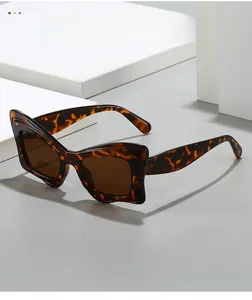Détail de lunettes de soleil œil-de-chat écaillées avec verres marron sur blocs blancs