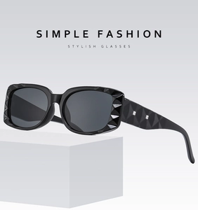 Detail of black square sunglasses with diamond-textured frame and metal rivets