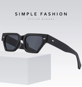 Détail de lunettes de soleil noires à monture épaisse avec rivets sur bloc blanc