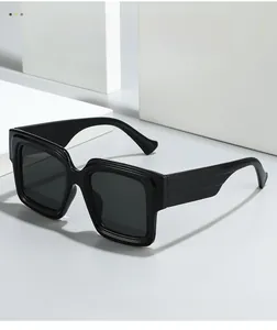 Detail view of bold black square oversized sunglasses with wide temples on white blocks
