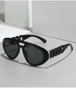 Détail de lunettes aviateur noires avec branches en chaîne et accents métalliques dorés