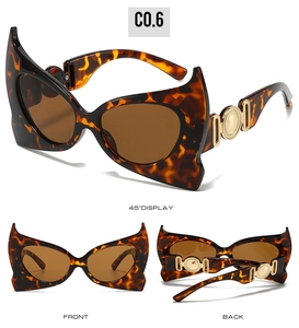 Detail view of tortoiseshell bat-shaped sunglasses with golden metal temple accents